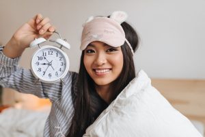 brown-eyed-woman-high-spirits-keeps-alarm-clock-smiles-looks-into-front_197531-19587