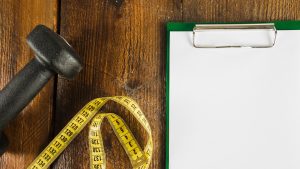 elevated-view-dumbbell-measuring-tape-blank-paper-with-clipboard_23-2147882103