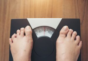 woman-feet-standing-weight-scale-wooden-background_1150-5134